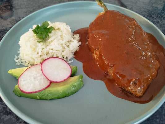 Chile relleno dipped in red mole sauce