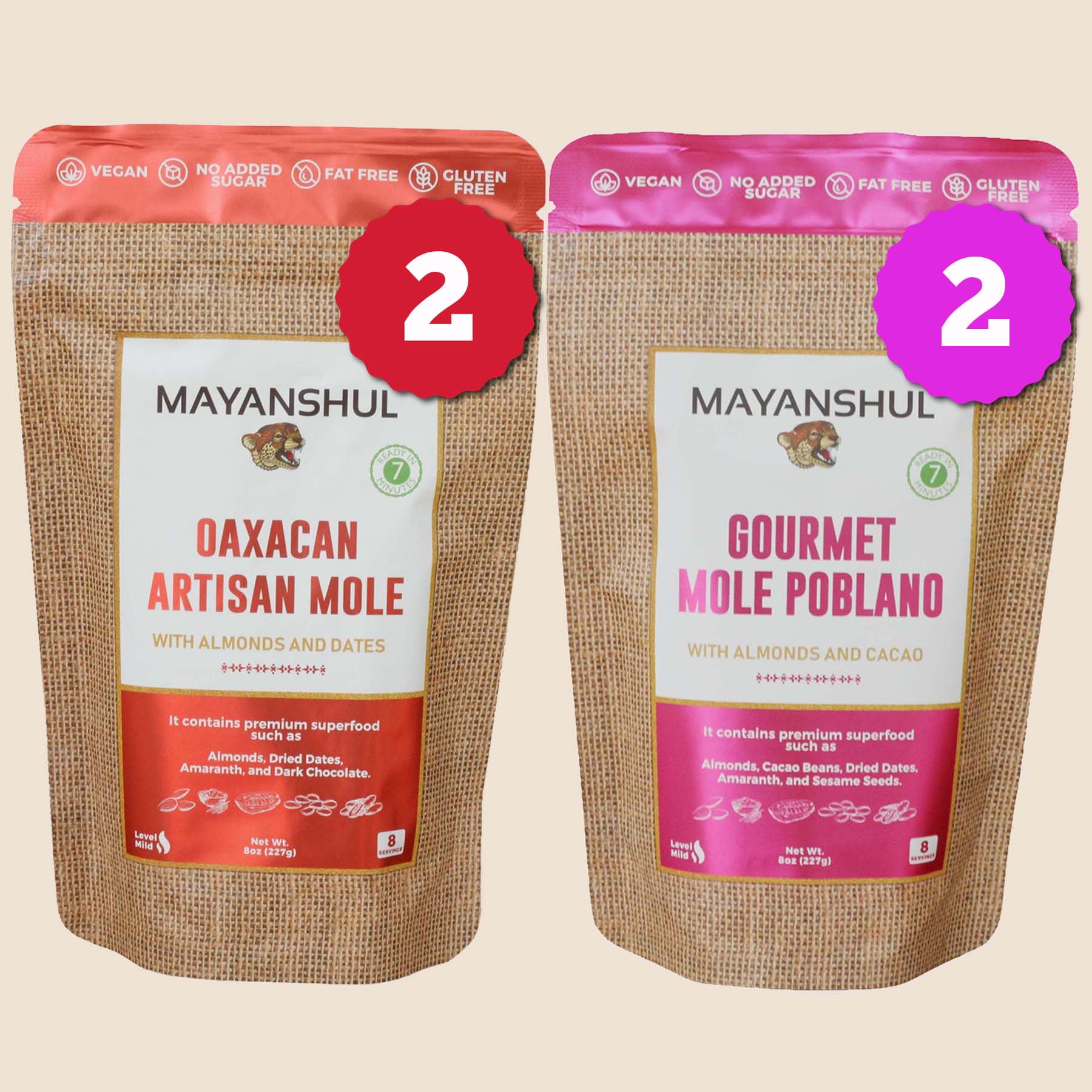Two packages of Mayanshul mole sauce powder, one labeled as 'Oaxacan Artisan Mole' and the other as 'Gourmet Mole Poblano', with pink and red seals respectively.